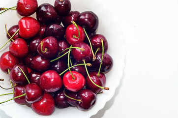 Obraz na płótnie Canvas Красная вишня с зеленой веточкой на белой тарелке