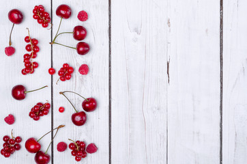 Ripe berries: raspberries, currants and cherries on a wooden table top view with space for text.