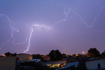 Thunder storm over houses in country side in the middle of the night with beautiful lightning in background