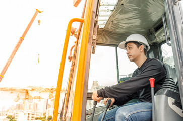 Fototapeta na wymiar Asian man operator driving backhoe on construction zone. To destroy the old building