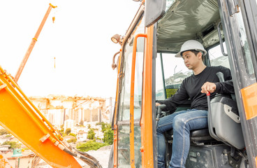 Fototapeta na wymiar Asian man operator driving backhoe on construction zone. To destroy the old building