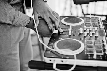 African american dj in huge white headphones creating music on mixing panel. Black and white photo.