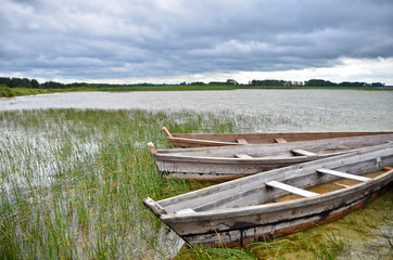 Obraz premium Old rustic wooden fishing boats on the lake at stormy weather, close up