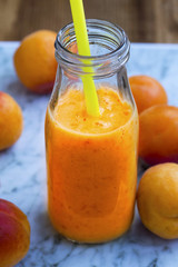Apricot smoothie in a bottle with straw