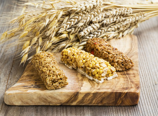 Muesli bars on wooden board with ears of wheat, oats, rye bouquet