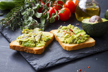 Smashed avocado on toast, tasty healthy appetizers with cherry tomatoes and herbs, olive oil