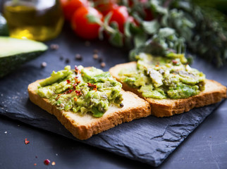 Smashed avocado on toast, tasty healthy appetizers with cherry tomatoes and herbs, olive oil