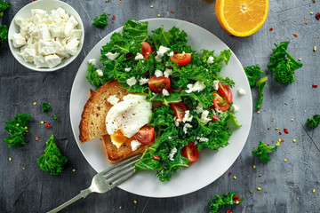Breakfast Green Kale with poached eggs, feta cheese, tomatoes and toast. healthy food
