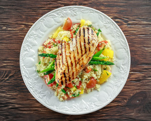 couscous salad with grilled chicken and asparagus on white plate. wooden rustic table. healthy food