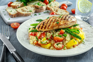 couscous salad with grilled chicken and asparagus on white plate. healthy food