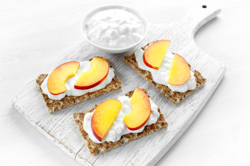 Homemade Crispbread toast with Cottage Cheese and nectarine on white wooden board.