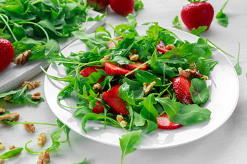 Fresh strawberry salad with arugula on white plate