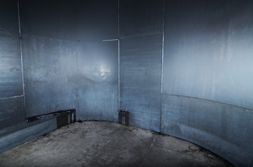 A scary cold  futuristic metal sheet prison cell, with a harsh concrete floor. An empty blue metal...