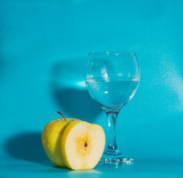 on a blue background yellow Apple with a glass of water.