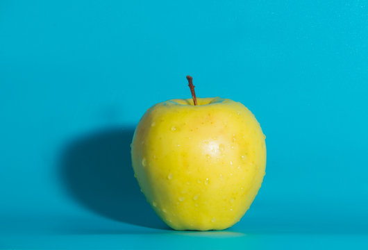 on a blue background yellow Apple, close up.