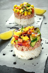 Tuna sushi stacks with mango, cucumber, tomatoes salsa served with balsamic vinegar, nigela ans sesame seeds