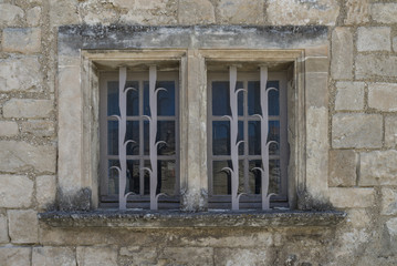 Fototapeta na wymiar Old, worn window with ornamented iron bars in Les Baux, France