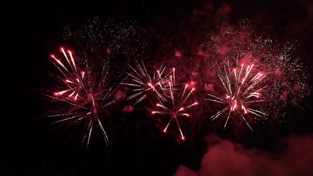 Volleys of celebratory fireworks in the night sky. Slow motion