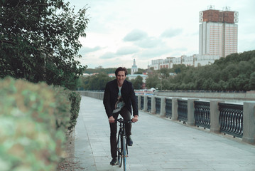 A man is riding a bicycle in a park on the waterfront