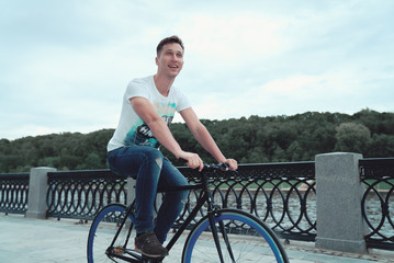A man is riding a bicycle in a park on the waterfront