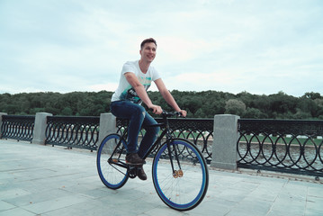 A man is riding a bicycle in a park on the waterfront