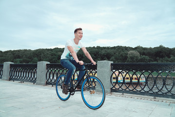A man is riding a bicycle in a park on the waterfront