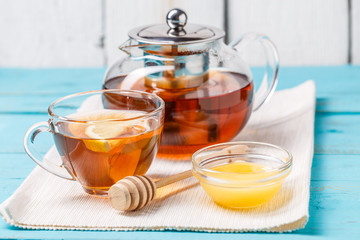Glass cup of tea with lemon, glass teapot and honey.