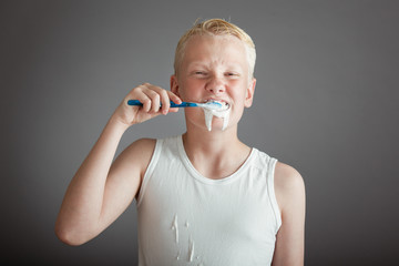 Cute blond boy brushing his teeth