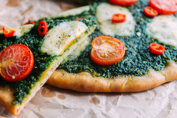 Appetizing pizza with pesto mozzarella and cherry and chili peppers