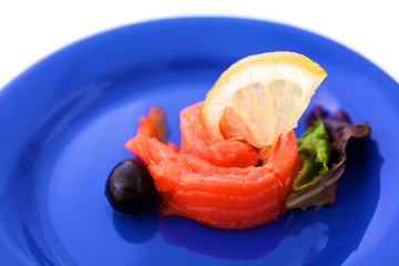 Slice of salmon with lemons and olives on a plate