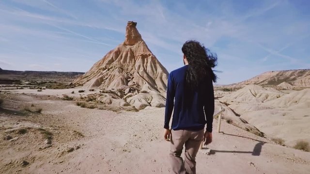 Hand held wide angle shot of native american navajo man walking through desert on hot sunny summer day, his hair is blowing in wind representing freedom and self exploration