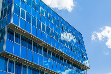 Fototapeta na wymiar Facade of a modern building. Glass Windows reflected the sky and clouds. Blue gamma.