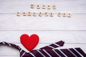 Happy Father's Day inscription with colorful tie and red heart on wooden background floor backround.