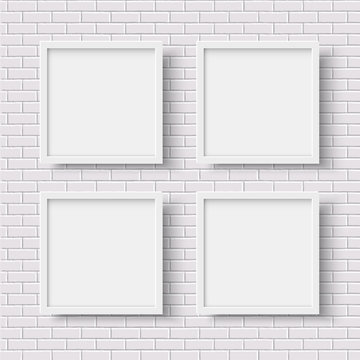 Four white square empty frames on white brick wall