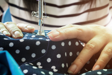 Woman's hand on sewing machine.Dressmaker work on the sewing machine.Tailor making a garment in workplace.Hobby sewing fabric as a small business concept