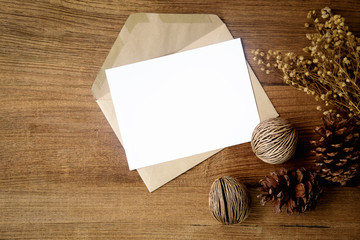 Top view of envelope and blank greeting card with rose flowers on white wooden background.