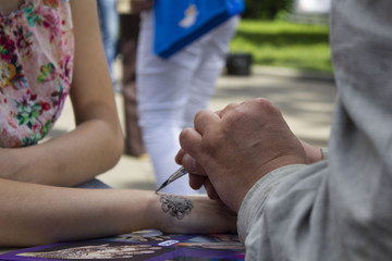 young woman mehendi artist painting henna on the hand