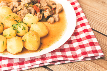 Goulash with meat, vegetables and potatoes on wooden table.