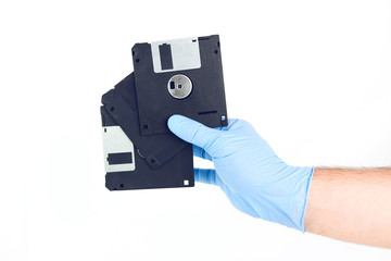 Hand With Gloves Holding Old Floppy Disks On Isolated Background