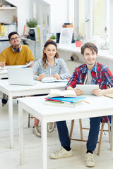 Group of college learners sitting by desks at lesson