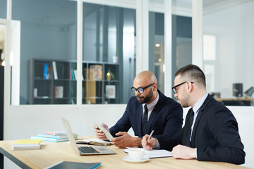 Two office managers with touchpad looking through online data