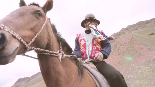 Peruvian muleteer mounts horse wearing the typical costume of the highlands. Slow motion