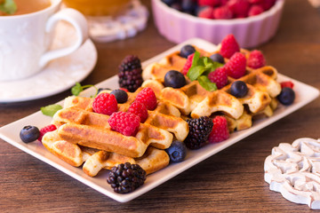 Belgium waffles with raspberries, chocolate and syrup on a plate.