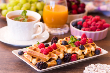 Belgium waffles with raspberries, chocolate and syrup on a plate.