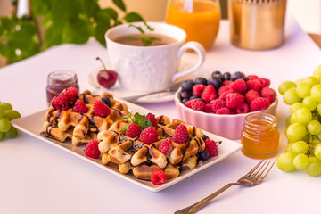 Belgium waffles with raspberries, chocolate and syrup on a plate.