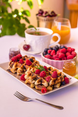 Belgium waffles with raspberries, chocolate and syrup on a plate.