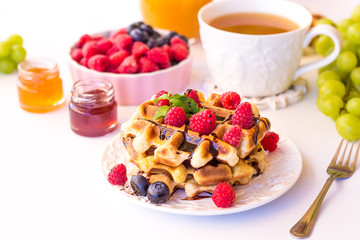 Belgium waffles with raspberries, chocolate and syrup on a plate.