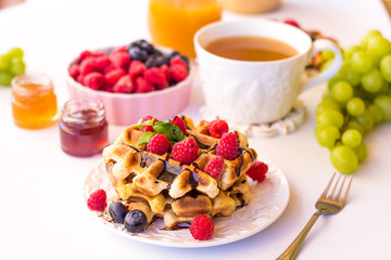 Belgium waffles with raspberries, chocolate and syrup on a plate.
