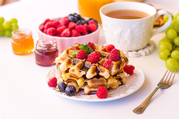 Belgium waffles with raspberries, chocolate and syrup on a plate.