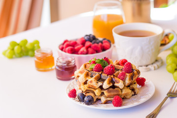 Belgium waffles with raspberries, chocolate and syrup on a plate.